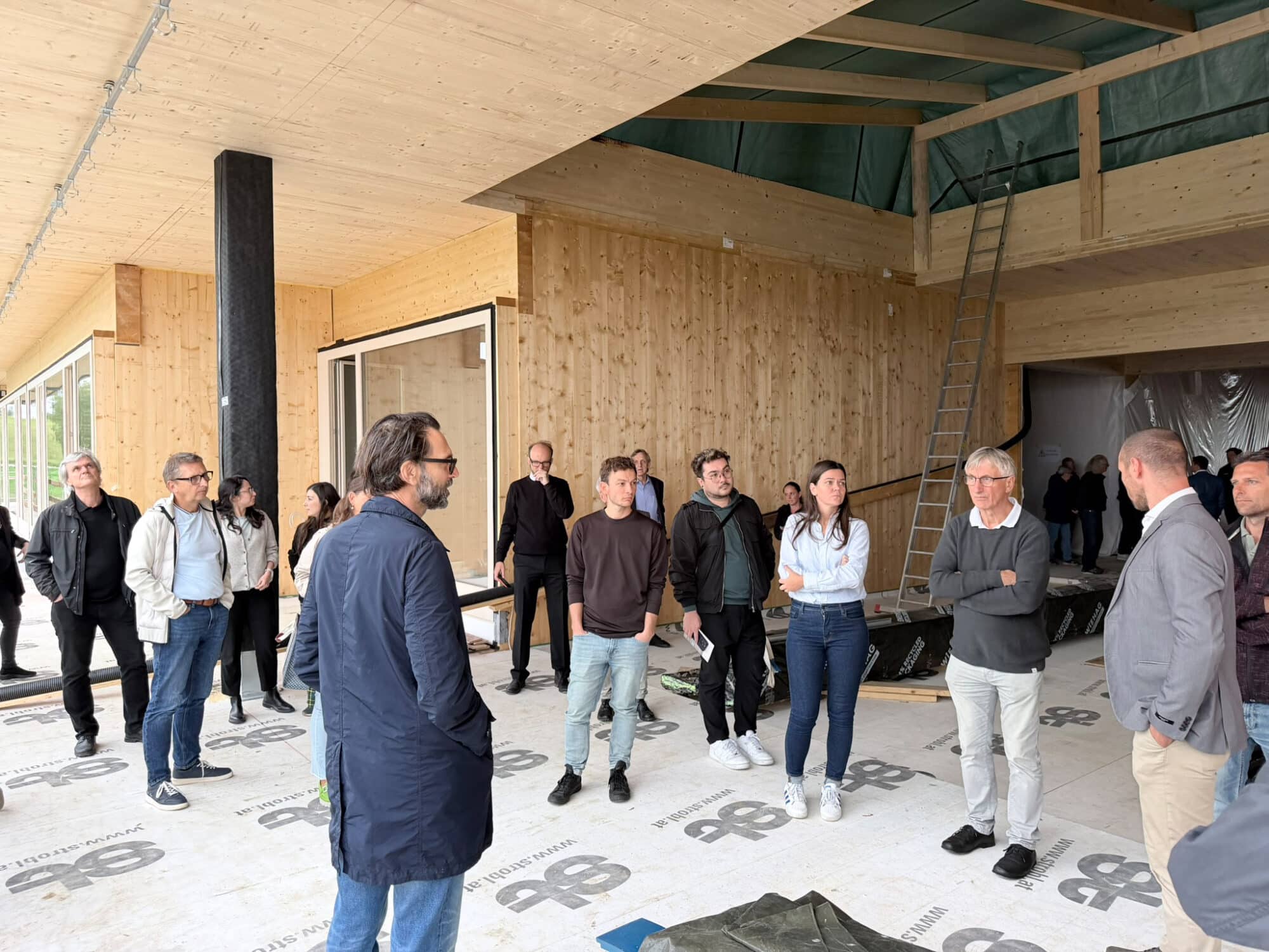 Besucher inspizieren Holzbau-Projekt in Österreich mit vielen Personen