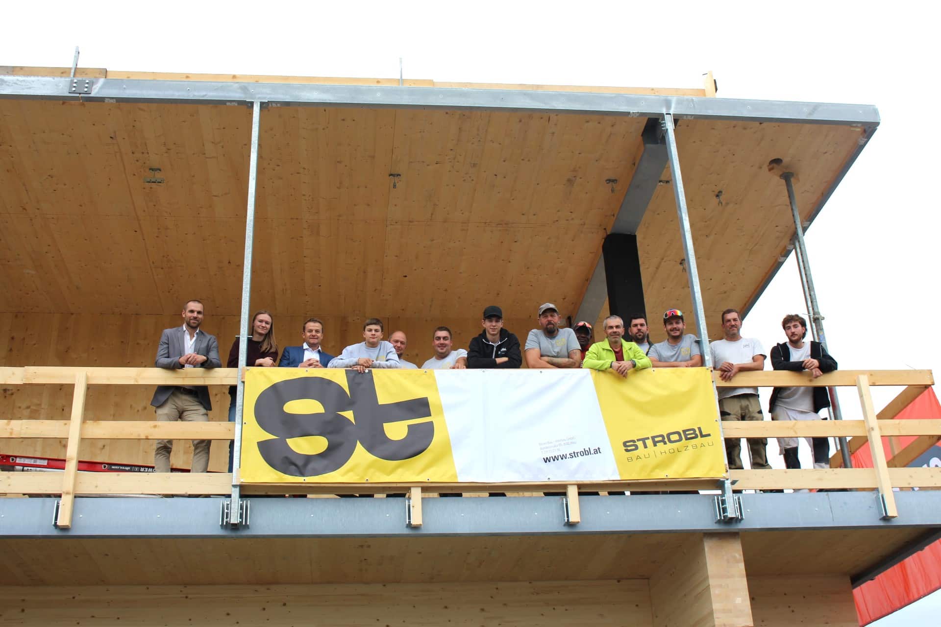 Strobl Bau Holzbau-Team mit Gästen auf Baustelle in Österreich